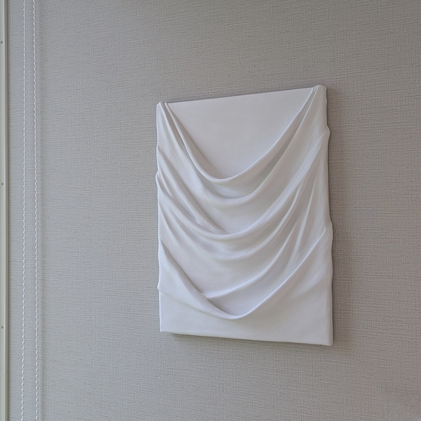 白のドレープが幾重にも重なり、やわらかな陰影を生む一点ものの立体アート