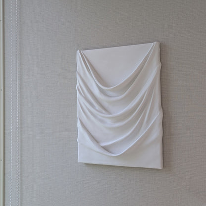 白のドレープが幾重にも重なり、やわらかな陰影を生む一点ものの立体アート