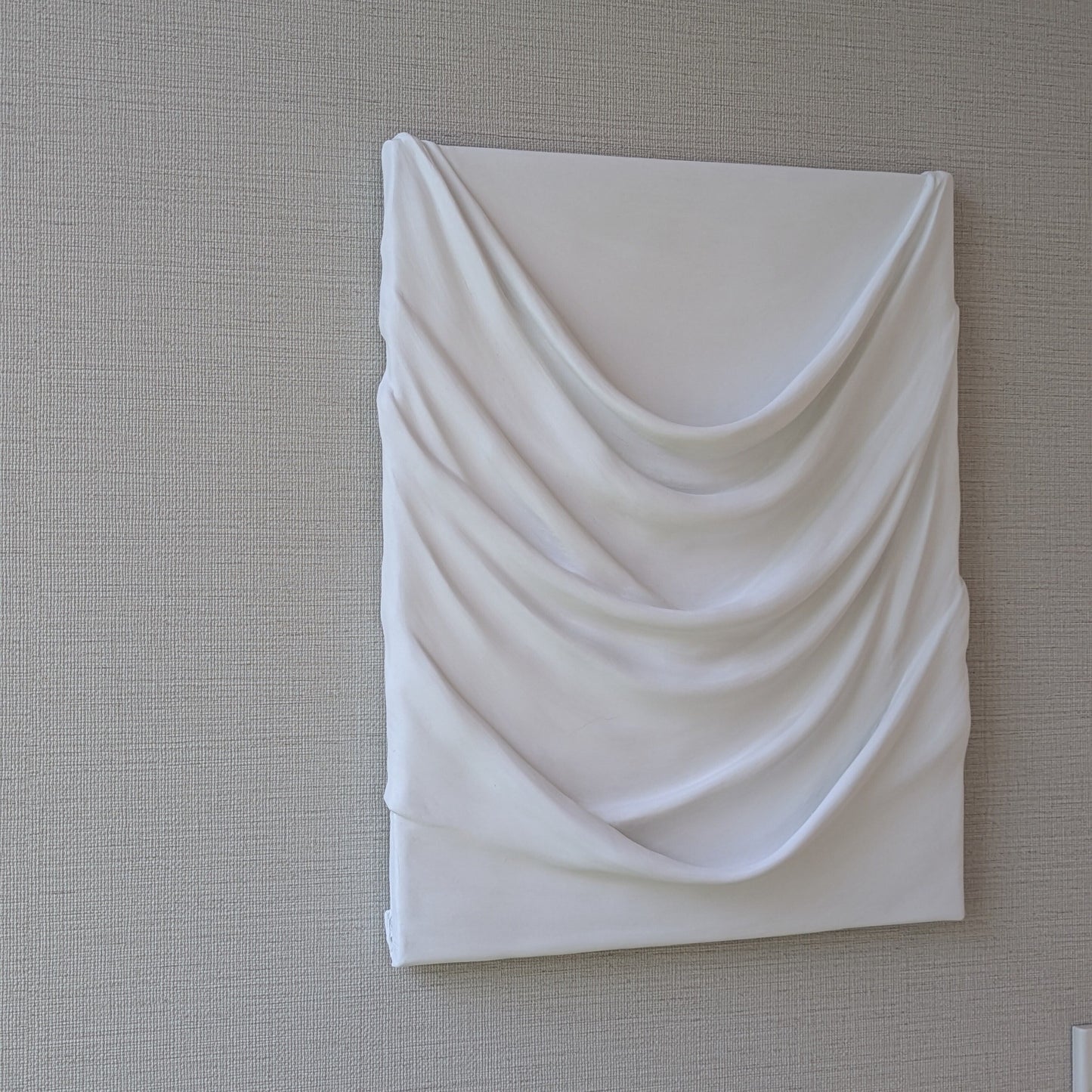 白のドレープが幾重にも重なり、やわらかな陰影を生む一点ものの立体アート