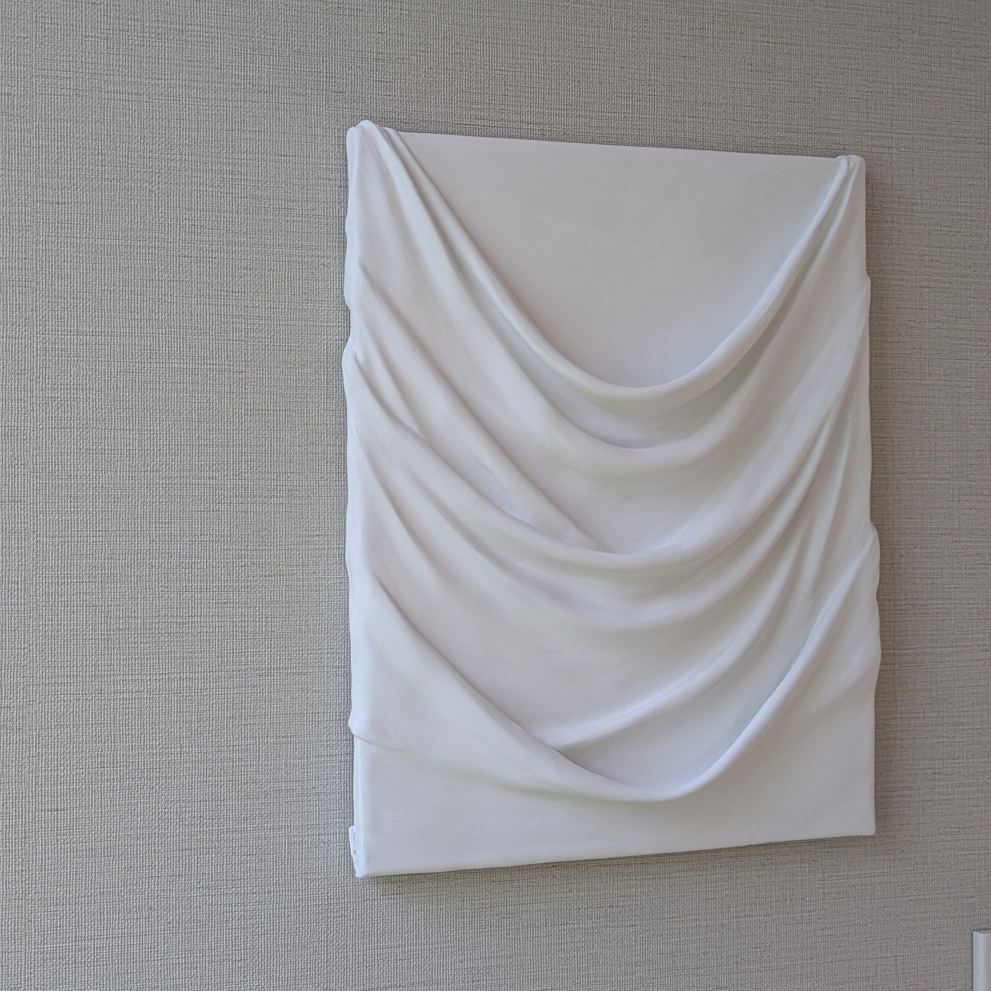 白のドレープが幾重にも重なり、やわらかな陰影を生む一点ものの立体アート